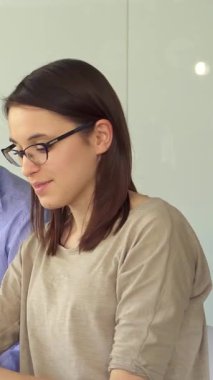 Canlı bir sahne, parlak, güneşli bir ofiste tutkuyla iş birliği yapan genç profesyonelleri yakalıyor. Mavi tişörtlü yakışıklı esmer bir adam dizüstü bilgisayarında odaklanmış kızıl bir kadınla görüşlerini paylaşırken, aynı zamanda çekici sakallı bir adam...