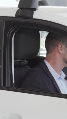 İyi bakımlı sakallı neşeli, yakışıklı bir adam, parlak bir galeride yeni bir arabanın modern iç güzelliği karşısında büyülenir. Işıl ışıl gülüşü ve şık giyimi mükemmel bir şekilde harmanlanmış lüks bir araç seçmenin heyecanını yansıtıyor.