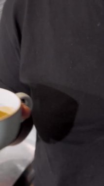Kendini adamış bir barista, el değmemiş beyaz bir kahve fincanına kadife gibi sıcak süt dökerek yüzeyde dans eden karmaşık latte sanatını icra eder. Bu büyüleyici an, kahve işçiliğinin tutkusunu ve hassasiyetini yakalar.