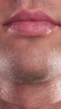 Bu çarpıcı yakın plan, yakışıklı bir gencin ağzını yakalıyor ve ciddi bir ifadeden sıcak, davetkar bir gülümsemeye geçiyor. Göz kamaştırıcı beyaz dişlerini gösteriyor. Pürüzsüz, siyah bir arkaplan üzerine kurulmuş bu resim gençliğini vurguluyor.