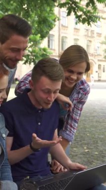 Güneşli bir kampüs gününde dizüstü bilgisayarın etrafında toplanan dört öğrenciden oluşan canlı bir grup kahkahaya boğuldu. Yakışıklı sarışın adam ve güzel kızıl kız bir bankta otururken, neşeli sınıf arkadaşları arkada durup arkadaşlıklarını yayıyorlar.