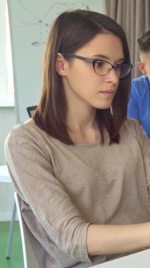 Kendine güvenen esmer bir kız, parlak, modern bir ofis masasında parlak bir dizüstü bilgisayarında yazı yazarken baş parmağıyla ışıldıyor. Arkasından, üç meşgul iş arkadaşı canlı bir tartışmada fikirlerini paylaşıyor, ilham verici bir işbirliği ortamı yaratıyor ve