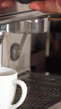 Yetenekli bir barmen kahve makinesinin üzerinde ustalıkla kaynar suyu lekesiz beyaz bir fincana yönlendirir. Bu yakın çekim, bira yapımının narin sanatını yakalar, zengin aromayı ve mükemmel bir fincan kahvenin beklentisini uyandırır.