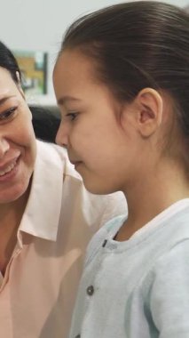 Neşeli bir Asyalı anne, parlak, davetkar bir kitaplıktaki renkli kitapların olduğu bir dizi kitabı zevkle incelerken küçük kızına ışıldıyor. Bu yürek ısıtan an, aile bağlarının ve paylaşılan zevklerin özünü güzel bir şekilde gözler önüne seriyor.