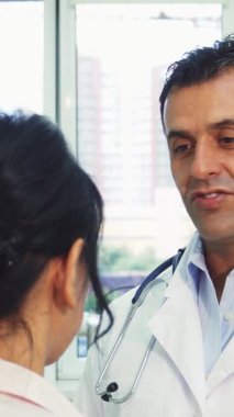 Modern dekor ile süslenmiş güneşli bir ofiste, sıcak kalpli bir doktor genç bir kadınla anlamlı bir diyalog kuruyor ve ona paha biçilmez sağlık anlayışları sunuyor. Adam nazikçe omzunu okşayarak güven ortamı yaratırken bağlantıları derinleşiyor.