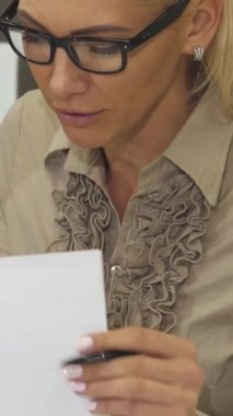 Bu yakın plan çekimde iki iş kadını, profesyonellik ve takım çalışmalarını vurgulayarak önemli belgeler üzerinde hararetli bir tartışmaya daldı. Renkli çizelgeler ve grafiklerle süslenmiş canlı ofis ortamı atmosferi güçlendirir.