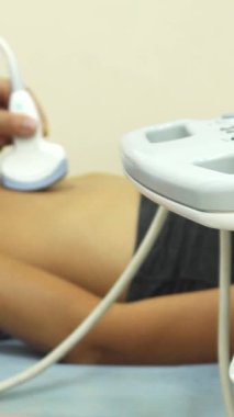 Huzurlu bir doktor ofisinde, kendini işine adamış bir doktor genç bir kadının elini nazikçe muayene eder, onun rahatını ve iyiliğini sağlar. Olay yeri gösterişli tıbbi ekipmanlarla süslenmiş. Bu hayati sağlık için profesyonel ama misafirperver bir ortam yaratıyor.