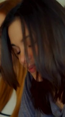 Hoş bir bayan öğrenci, dalgalı siyah saçlı, neşeli bir konferans salonunda neşe içinde saçlarına dokunuyor. Bu yakın plan onun ışıl ışıl gülümsemesini nişanlı sınıf arkadaşlarının arasında yakalıyor ve davetkar bir atmosfer yaratıyor.