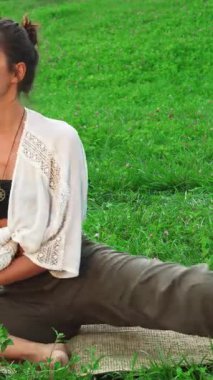 Işıl ışıl genç bir kadın canlı yeşil çimlerle çevrili doğal bir paspasın üzerinde rahat bir şekilde oturur. Neşeli gülüşü ve sakin tavırları huzur ve pozitiflik yayıyor, sağlıklı bir yaşam tarzının ve iç huzurunun özünü somutlaştırıyor.