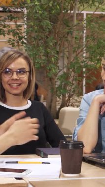 Canlı, modern bir ofiste, karizmatik bir genç adam, iki ilgili bayan meslektaşıyla fikirlerini tutkuyla paylaşırken hareketli bir şekilde hareket eder. Yeşilliklerle ve rahat bir atmosferle çevrelenmiş bir şekilde bir dizüstü bilgisayar ve kahve eşliğinde işbirliği yaparlar.