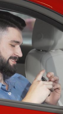 Şık sakallı ışıldayan bir adam yeni göz kamaştırıcı kırmızı arabasının anahtarlarını elinde tutuyor. Sürücü koltuğundan heyecan ve gurur yayıyor. Bu canlı an, sahipliğin heyecanını ve yeni maceralara atılmanın verdiği hazzı özetliyor.