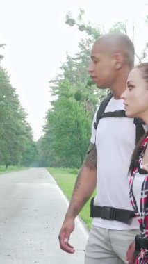 Maceracı, çok ırklı bir çift, huzurlu bir kırsal yolda başparmakları havada bir gezinti için sabırsızlıkla bekliyor. Canlı sırt çantaları ve ışıl ışıl gülümsemeleriyle, keşif ve neşe dolu bir ruh yayarlar, ilerideki yolculuğu kucaklamaya hazırdırlar.