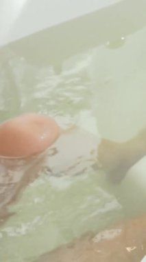 Güzel bir kadın, kaynayan bir girdap banyosunda rahatlayarak onu sıcak, rahatlatıcı bir suyla saran gençleştirici bir hidroterapinin tadını çıkarıyor. Sakin atmosfer ve hidroterapi jetlerinin nazik okşaması onun huzurunu artırmak için keyifli bir geri çekilme yaratıyor.