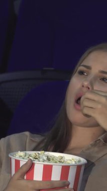 Loş bir sinemada, genç bir çift yan yana oturur, kız patlamış mısır yerken ve bej bir bluz giyerken, erkek arkasına yaslanır, can sıkıntısından gözleri yarı kapalı olarak. İfadeleri, heyecan arasındaki katı zıtlığı açıkça gösteriyor.