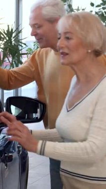 Yaşlı, zevkli bir beyaz çift galeride şık bir aracı inceliyor ve kadın nazikçe arabanın kapısına dokunuyor. Sofistike gri saçlı adam, karısının yanında gururla duruyor. İkisi de bu heyecan verici maceraya atılırken mutluluktan uçuyor.