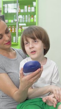 Canlı bir eczane koridorunda annesiyle duş jeli seçeneklerini tartışan sevimli küçük bir çocuk heyecanla ışıldıyor. Renkli sağlık ve güzellik ürünleriyle çevrelenmiş neşeli etkileşimleri sıcaklığı ve ailenin özünü yayıyor.