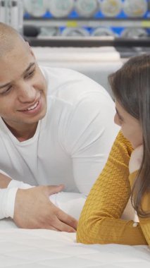 Hoş, genç bir çift, hayat dolu bir mobilya dükkanındaki lüks bir şiltenin üzerinde gevşeyip şakalaşıyor ve cilveli bakışlar atıyor. Neşeli bağlantıları ve yumuşak titreşimleri mükemmel yatağı keşfederken sevgi ve konforun özünü yakalar.