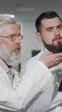 Parlak ve modern bir hastane koridorunda, genç bir erkek doktor ve deneyimli kıdemli meslektaşı, hastaların sağlığıyla ilgili hayati bir tartışma içine girerek MRI taramasını dikkatle inceliyor. Yoğunlaşmış ifadeleri ve beyaz laboratuvar önlükleri