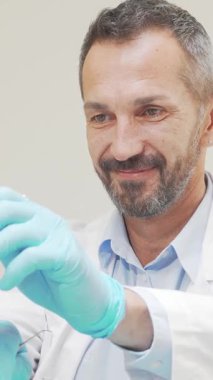 Mavi eldivenli ve beyaz ceketli yetenekli bir erkek dişçi parlak, modern bir klinikte tanınmayan bir kadının dişlerini inceliyor. Onun güven verici gülümsemesi ve profesyonel yaklaşımı rahatlatıcı bir atmosferi teşvik ediyor.