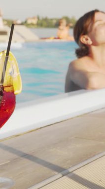 Neşeli genç bir kadın, sıcak güneşin tadını çıkarıyor. Kahkahaları, bir dilim limonla süslenmiş canlı bir kokteylin tadını çıkarırken, hafif su damlalarıyla karışıyor. Bu huzurlu sahne yaz mutluluğunun özünü yakalar, mutluluk saçar ve...