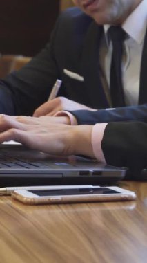 Bu yakın çekim gösterilerinde bir iş kadını zarif bir dizüstü bilgisayarın üzerinde dans ederken bir işadamı yanında önemli notlar kaleme alıyor. Yumuşak ışığın sıcacık parıltısı ve parlak ahşap masanın zengin dokusu profesyoneli güçlendirir.