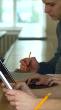 Kafkas ve diğer etnik kökenler de dahil olmak üzere çeşitli genç yetişkinler, çeşitli not tutma tekniklerini sergiledikleri iyi aydınlatılmış bir üniversite konferans salonuna daldılar. Bazı öğrenciler özenle dizüstü bilgisayarlarda yazarken, diğerleri tutkuyla yazıyorlar.