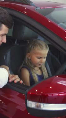 Kendini adamış bir baba açık pencereden sarkmış, kızına arabalarda rehberlik ediyor ve kızına direksiyon başında güvenle oturuyor. Canlı kırmızı araba galerisindeki neşeli değiş tokuşları sıcaklığı ve bağlantıyı yansıtıyor.