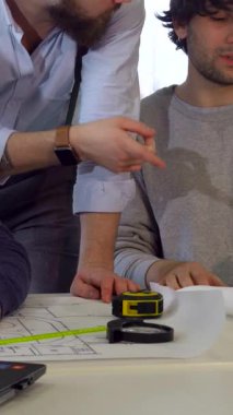 Üç Kafkasyalı mimar, canlı planlar ve proje belgeleriyle çevrili, parlak bir çalışma masasında tutkuyla beyin fırtınası yapıyorlar. Gıcır gıcır beyaz gömlekli ve pantolon askısı takmış sakallı esmer bir adam öne eğiliyor ve meslektaşlarına rehberlik ediyor.