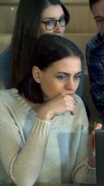 Hem erkek hem de kadın öğrencilerden oluşan çeşitli bir grup, çağdaş bir konferans salonunda bir dizüstü bilgisayar üzerinde derin bir tartışmaya giriştiler. Odaklanmış ifadeleri ve hareketli hareketleri, canlı bir merak atmosferini yansıtıyor.