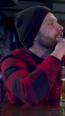 İki sakallı arkadaş, biri canlı kareli gömlekli, diğeri de rahat çizgili kazaklı, neşeli bardaki favori spor takımlarına coşkuyla tezahürat eden iki arkadaş. Önlerinde buz gibi bira bardakları tokuşturarak yumruklarını saf bir şekilde kaldırıyorlar.