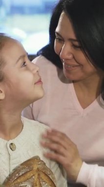 Işıl ışıl, olgun bir Asyalı kadın ve sevimli küçük kızı ışıl ışıl gülümseyip, enfes hamur işleriyle dolu canlı bir fırının önünde başparmaklarını kaldırıyorlar. Bu yürek ısıtan an güzellikle neşeyi özetliyor.