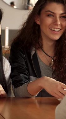 Şık bir şehir kafesinde, üç modaya uygun genç kadın canlı Asyalı bir kadının hareketli bir şekilde arkadaşına doğru hareket etmesiyle heyecanlı bir sohbete girişiyor. Kıvırcık saçlı beyaz kadın zarif beyaz bardağına uzanırken neşeyle ışıldıyor.