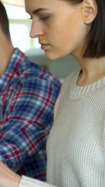 Tarz sahibi, genç, beyaz bir kadın tabletle etkileşime geçiyor ve hevesli sınıf arkadaşlarıyla dolu canlı bir konferans salonuna güven saçıyor. Parlak esmer saçları kameraya döndüğünde yüzünü çerçeveliyor. Etrafındaki akranları ise dikkatle kameraya odaklanıyor.