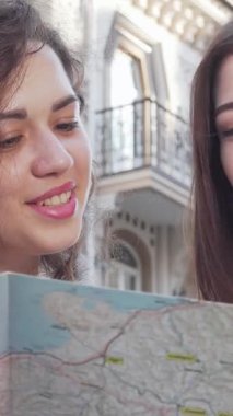 Canlı bir şehir ortamında, biri kıvırcık saçlı, diğeri düz bukleli iki genç kadın, ayrıntılı bir haritayı hevesle inceliyor, yüzleri heyecan ve merakla parlıyor. Bu büyüleyici an maceranın özünü yakalar ve...