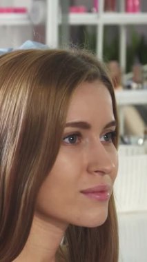 Bu büyüleyici yakın planda, yetenekli bir kadın kuaför muhteşem genç müşterisinin saçlarını kıvırarak saç şekillendirme sanatının karmaşıklığını gözler önüne seriyor. Modern aletlerle süslenmiş ve yumuşak, davetkar ışıkla yıkanmış şık bir salon,