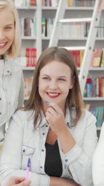 Değişik üniversite öğrencilerinden oluşan canlı bir grup üniversite kütüphanesinde, enerjik ve davetkar bir atmosfer yaratarak kahkaha ve fikirleri paylaşıyor. Neşeli ifadeleri ve hareketli tartışmaları arkadaşlığın ve işbirliğinin özünü yansıtıyor.