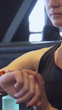 Bu canlı yakın planda, uzun sarı saçlı, parlak at kuyruklu odaklanmış genç bir kız spor kol saatini ayarlıyor, heyecan verici bir antrenmana hazırlanıyor. Görüntü enerji ve kararlılık yayıyor, bağlılığını gösteriyor.