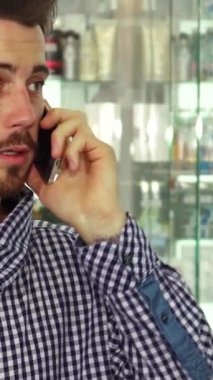 Odaklanmış esmer bir adam elinde renkli haplarla dolu bir şişeyi dikkatle inceliyor. Sağlıklı ürünlerle dolu canlı eczane raflarıyla çevrelenmiş, bilgilendirilmiş karar verme mekanizmasının özünü somutlaştırıyor.