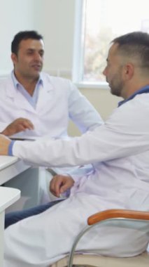 İyi aydınlatılmış bir muayenehanede, genç bir kadın başarılı atamasının bir simgesi olan tıp sertifikasını incelerken neşe saçıyor. Beyaz önlüklü özenli erkek doktorlarla çevrili sahne profesyonellik ve özen gösteriyor.