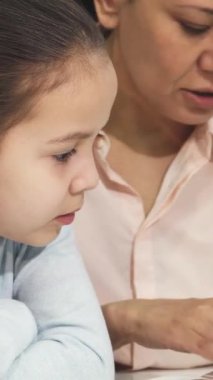 Bu dokunaklı yakın plan çekimde ilgili bir Asyalı anne ve sevimli kızı derin bağlarını vurgulamak için bir kitaba dalmışlar. Samimi kütüphane ayarı, bu samimi sahnenin sıcaklığını arttırır. Sevgi, öğrenme ve paylaşılan mutluluğun yayılması.