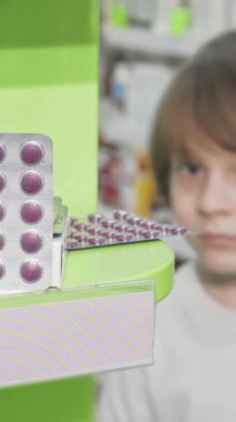 Neşeli küçük bir çocuk neşeli bir eczanedeki renkli su toplayan hapları ilginç bir şekilde inceliyor. Bu büyüleyici sahne, bir keşif ve refah yolculuğunu somutlaştıran sağlık ürünlerini incelerken çocukluğun mucizesini vurguluyor.