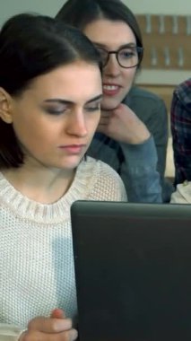 Değişik öğrencilerden oluşan dinamik bir grup, gülümseyen esmer bir kadın ve odaklanmış sakallı bir adam, parlak bir dizüstü bilgisayarın etrafında toplanıp fikir alışverişinde bulunuyorlar. Hayat dolu üniversite salonu, takım çalışmasının ve akademik çalışmanın ruhunu yansıtan enerjiyle uğulduyor.