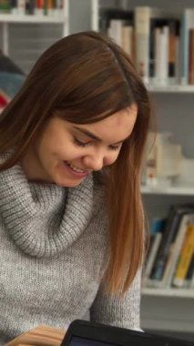 Sade gri kazaklı neşeli kahverengi saçlı bir kız parlak, davetkar bir kütüphanede düşünceli erkek sınıf arkadaşıyla bir kitaptan ilginç bir keşfi paylaşıyor. İki Kafkasyalı öğrenci arasındaki bu canlı etkileşim...