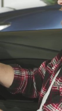 Kırpılmış bir fotoğraf, modaya uygun ekose gömlekli sakallı bir adamı sergiliyor. Galeride gösterişli, modern bir arabanın direksiyonunu sıkıca kavrarken kendine güveni tam. Bu dinamik görüntü araba alışverişinin heyecanını yakalıyor, lüks şeyleri vurguluyor.