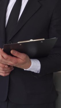 Keskin siyah takım elbiseli karizmatik bir satış müdürü, lüks tasarımını galeride sergileyen parlak gri bir sedana doğru emin adımlarla hareket eder. Elinde bir panoyla, potansiyel alıcıları zarif özelliklerini keşfetmeleri için davet ediyor.