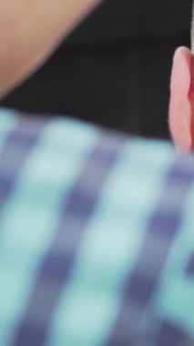 Bu canlı sahnede, bir berber bir kırpıcıyı ustalıkla manevra ettirir, erkek müşterisinin saç kesimini titizlikle şekillendirir. Berberin çarpıcı damalı gömleği zarif, modern berber dükkanının arka planına vurgu yaparak sanatın önemini vurguluyor.