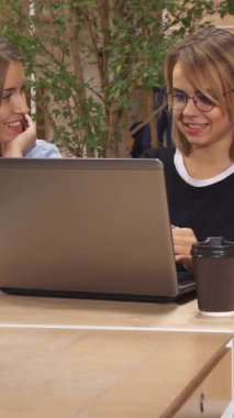 Neşeli, sarışın bir kız heyecan verici bir şekilde iş arkadaşlarının dizüstü bilgisayarını modern bir çalışma alanında keşfetmeleri için işaret ediyor. Yakınlarda, odaklanmış kahverengi saçlı bir kadın notlar alırken yakışıklı bir adam da kitaptan zevk alıyor ve canlı bir işbirliği ortamı yaratıyor.