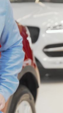 Heyecanlı bir adam şık giyimli bir araba satıcısından lüks, modern bir bayilikte araba anahtarlarını zevkle kabul eder. Parlak arabalarla dolu, parlak sergi salonu heyecan ve başarı yayar, özünü yakalar.