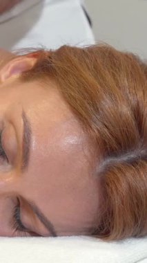 Kestane rengi saçları akan güzel bir kadın, yetenekli bir masör, omuzlarını ustalıkla ovalarken ve onu rahatlatıcı bir atmosferle sarmalarken huzur içinde uzanıyor. Yumuşak ışık ve sakinleştirici pastel renklerin ışıltısı lüks bir geri çekilme yaratır.