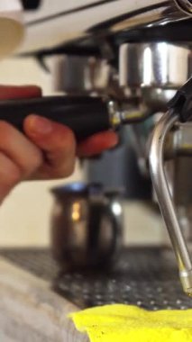 Kendini işine adamış genç bir adam ustalıkla şerbetini yeni demlenmiş bir fincan kahveye dolduruyor ve arka planda hafifçe vızıldayan pırıl pırıl kahve makinesi var. Odaklanmış elleri kahve yapma sanatını ortaya çıkarıyor, zengin lezzetleri harmanlıyor.